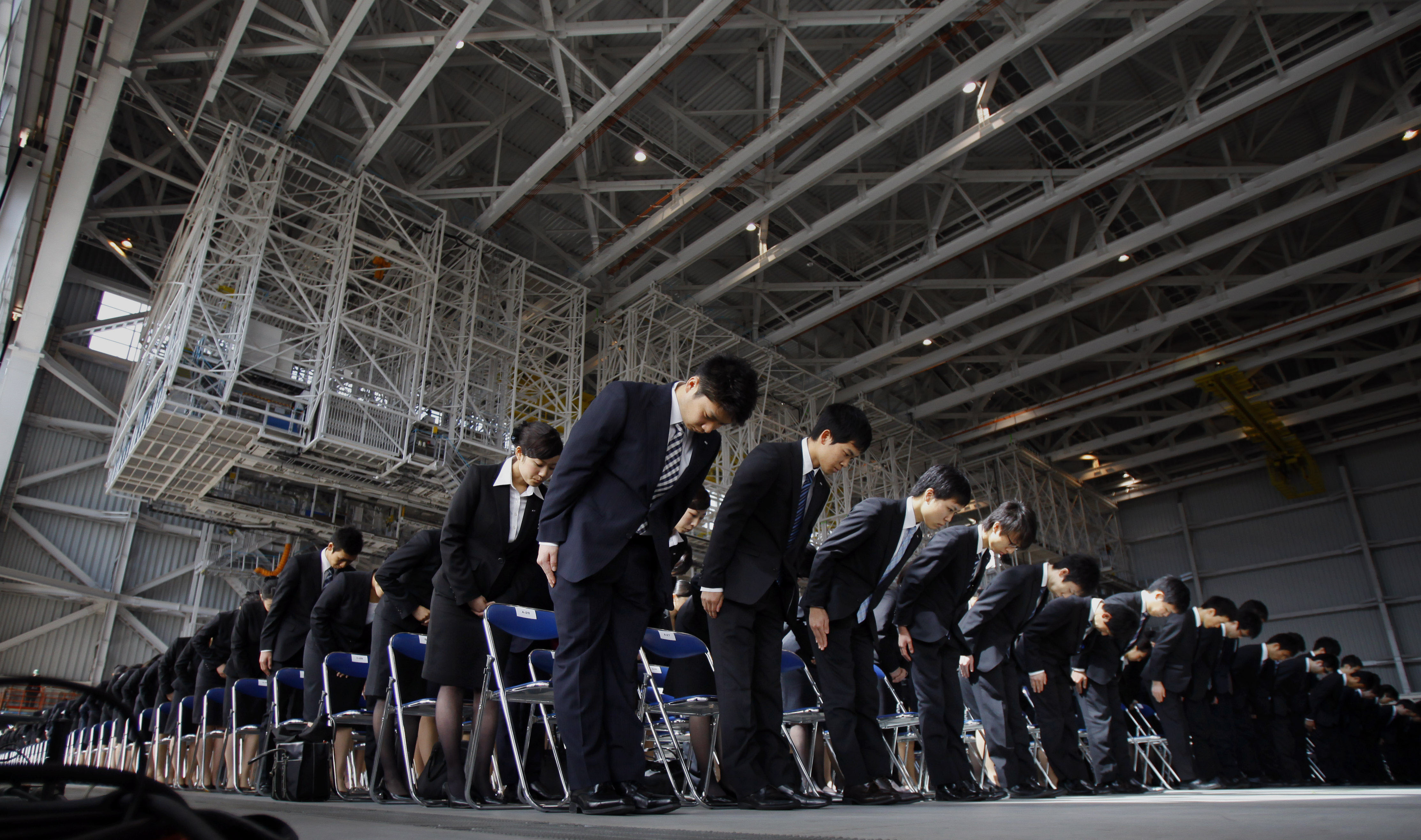 Newly hired employees of All Nippon Airways and ANA group companies bow during an initiation ceremony at the company's aircraft maintenance hangar in Haneda airport in Tokyo Monday, April 1, 2013. A total 1,068 new recruits attended the ceremony, according to the company. (AP Photo/Junji Kurokawa)
